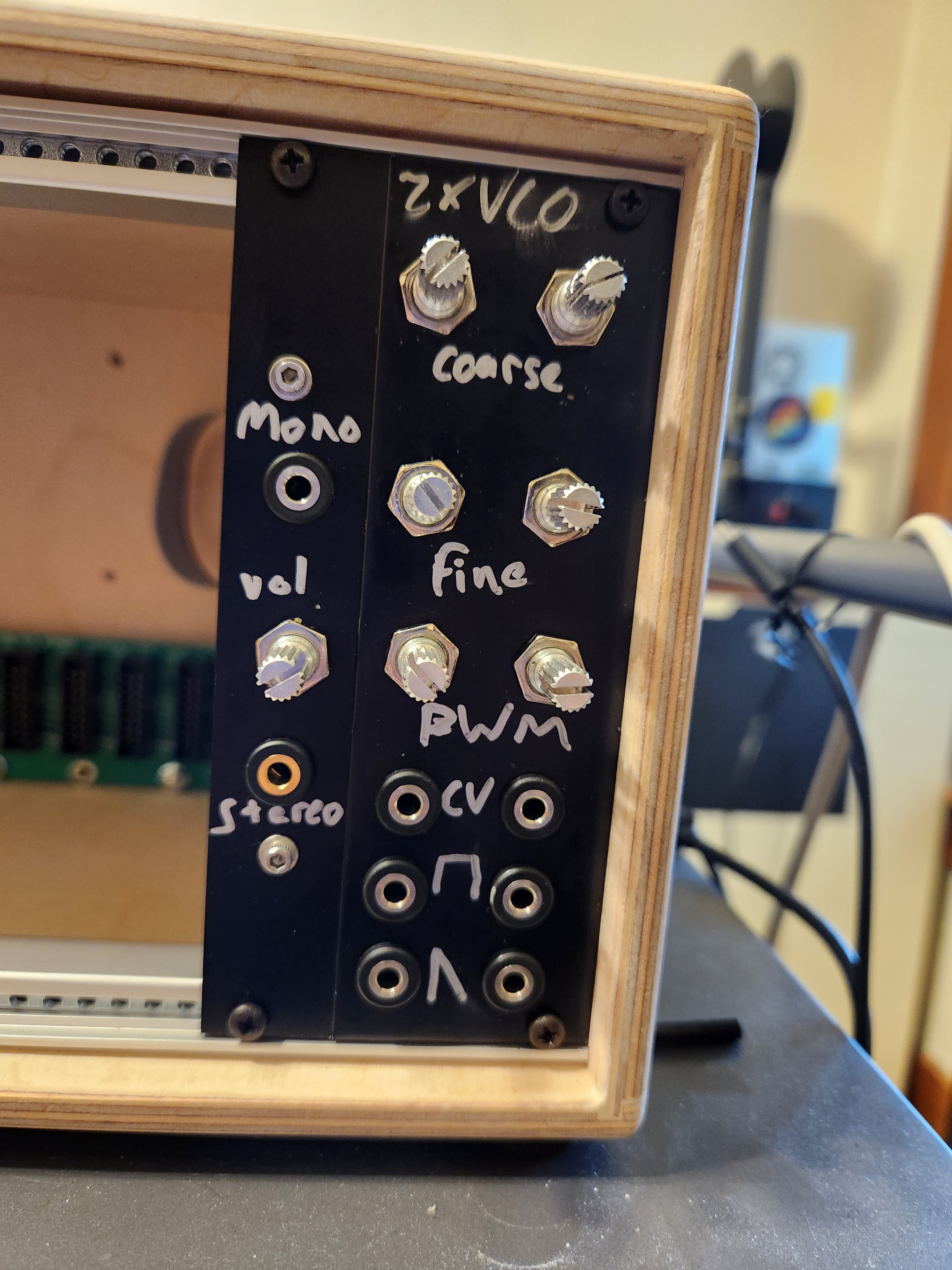 photo of two diy eurorack modules in a case. one has two jacks for mono in and stereo out and a
        volume knob. the other has 3 pairs of jacks for saw wave out, square
        wave out, and cv in. it also has 3 pairs of knobs for coarse and fine
        tuning and pwm. at the top it says '2xVCO'